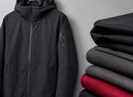 Charcoal technical jacket on a hanger beside folded fabric swatches